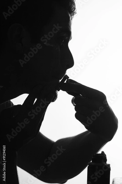 Fototapeta Silhouette man shaving using razor with cream foam