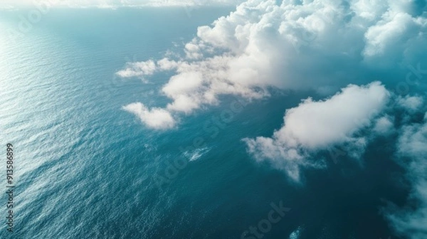 Fototapeta Top view of the ocean with a veil of fluffy clouds. A tranquil and dreamy scene from above, with the sea and sky intertwined.