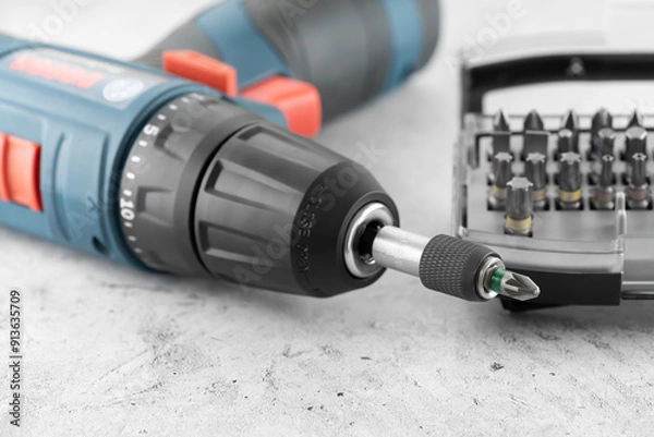 Fototapeta Professional cordless drill screwdriver and screwdriver bit set close-up. Quick-change universal holder with locking mechanism to ensure a secure hold and fast bits changes, emphasis on detail.