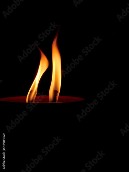 Fototapeta Two yellow Candle Flames burn on Black Background. Candle light burning at night isolated black. The warm, flickering light emitted by the candles, creating a serene and contemplative atmosphere.