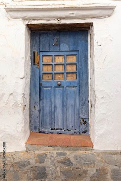 Obraz A weather blue door on a white stucco house.