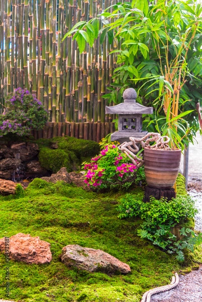 Obraz Minimal Japanese garden in home with small stone lantern and bamboo fountain and moss and flowers.

