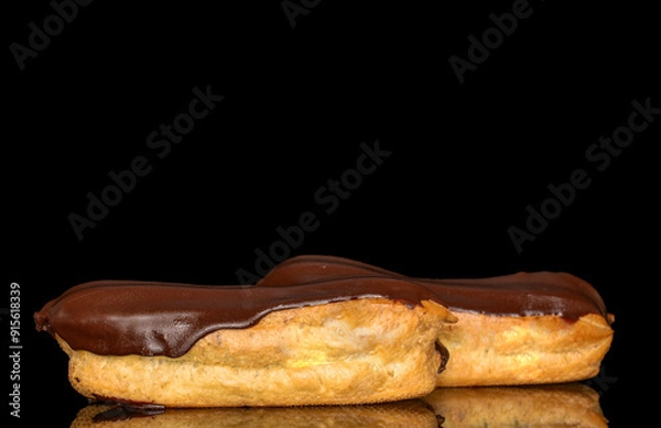 Fototapeta Two eclairs with cream, macro, isolated on a black background.