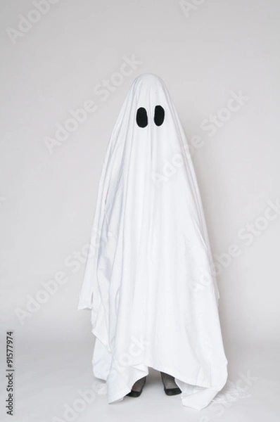 Fototapeta child dressed as a halloween ghost with his feet showing beneath the sheet