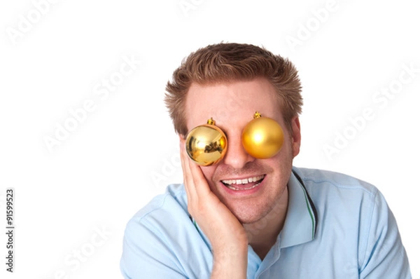 Obraz Junger lachender Mann mit Christbaumkugeln vor den Augen