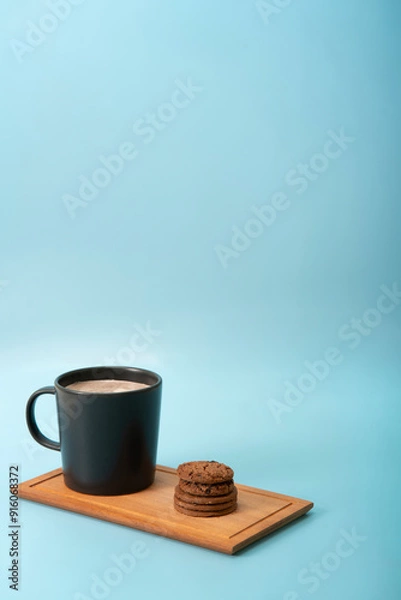 Fototapeta The chocolate chip cookie biscuit with a cup of chocolate on a blue background. 