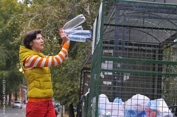 Fototapeta Woman throws plastic bottles to recycling container