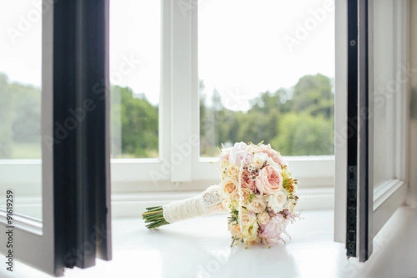 Obraz Elegant bridal bouquet of roses in light colors and pearl beads decoration lying on the windowsill.