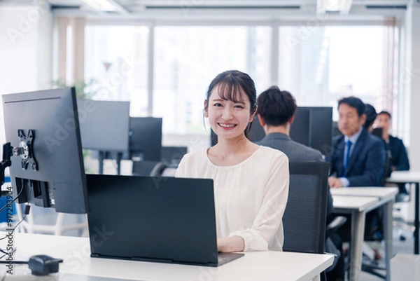 Fototapeta オフィスで笑顔でデスクワークをする若い女性