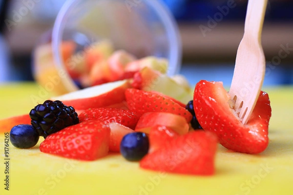 Fototapeta fruit cup tilted and fruits spilled and scattered with a wooden fork