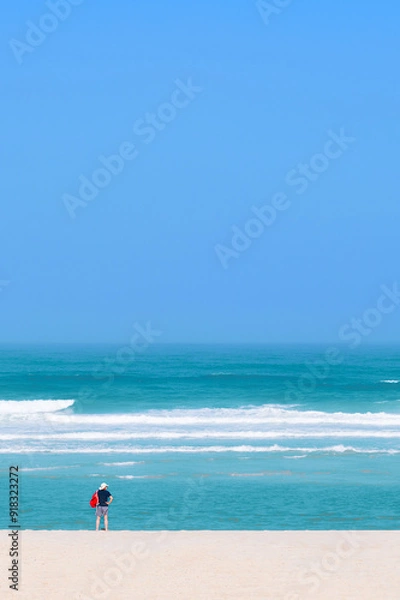 Fototapeta minimalism on the beach, with a sea in the background and an isolated person on one side