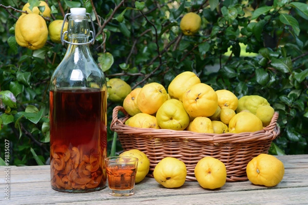 Fototapeta Tincture of quince and fruit in wicker basket on a wooden table.