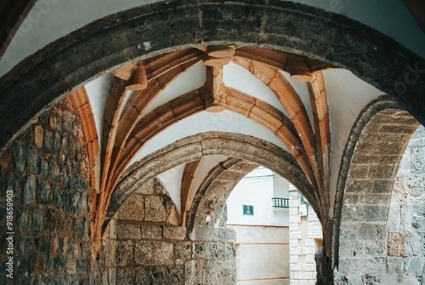 Fototapeta The arched doorway is made of stone and has a rustic feel to it
