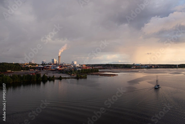 Fototapeta Industrial landscape with lake, stormy sky and factory during golden hour. Industry harmonized with nature concept