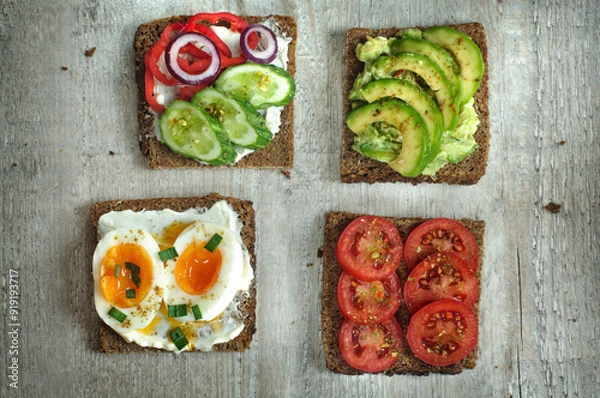 Fototapeta Four sandwiches on whole grain rye bread with egg and various vegetables. View from a high angle