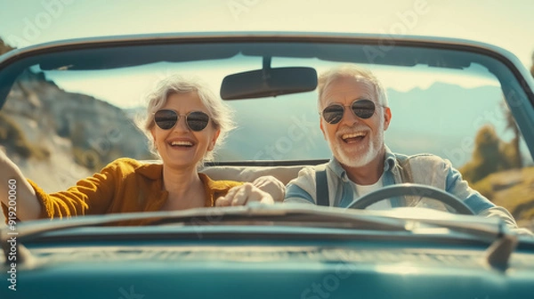Fototapeta A joyful senior couple during a road trip. They are happily seated in their car, with a picturesque view of the open road and countryside behind them