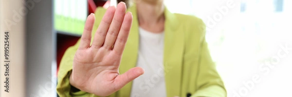 Fototapeta Female sitting in office and showing stop sign or protesting gesture