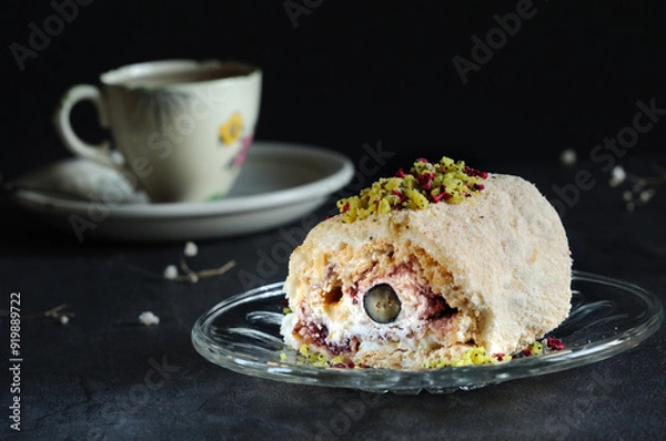Fototapeta Delicious meringue roll with cream and jam, on a saucer close-up. Selective focus, natural light