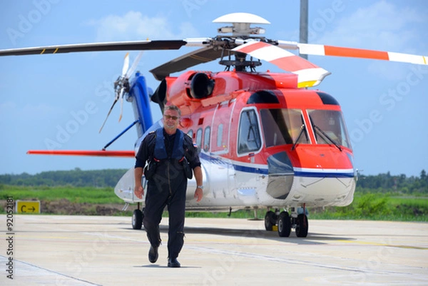 Fototapeta caucasian offshore helicopter pilot is walking and smiling besid