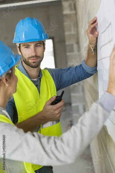 Fototapeta Engineers on building site checking plans