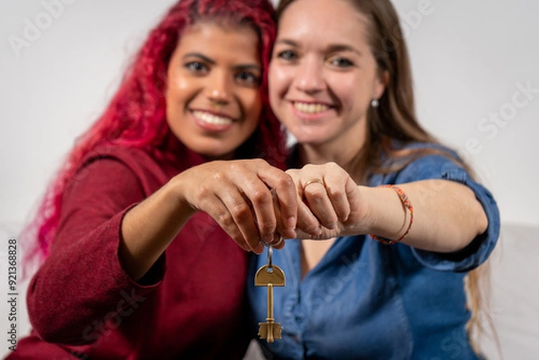 Obraz Pareja de mujeres sosteniendo una llave a cámara en señal de felicidad por adquirir su primera casa