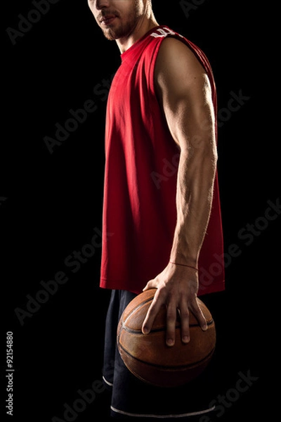 Obraz Basketball player holding ball isolated on black background