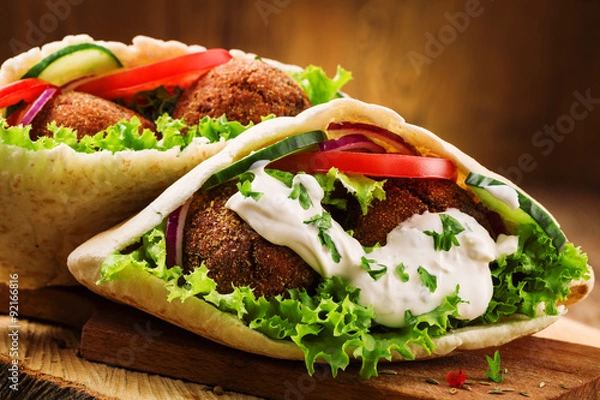Obraz Falafel i świeże warzywa w chlebie pita na drewnianym stole