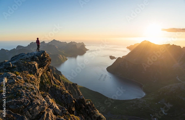 Fototapeta A woman enjoying the view and the midnight sun on the summit of Keipen, Senja.