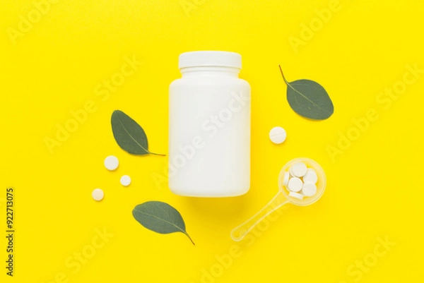 Fototapeta Bottle with pills and green leaves on color background, top view