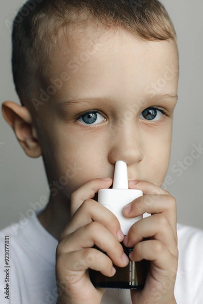 Fototapeta A sick child with a runny nose uses nasal spray to relieve congestion.Perfect for health, illness, and care themes. High-quality image of respiratory relief and treatment for cold and allergy symptoms