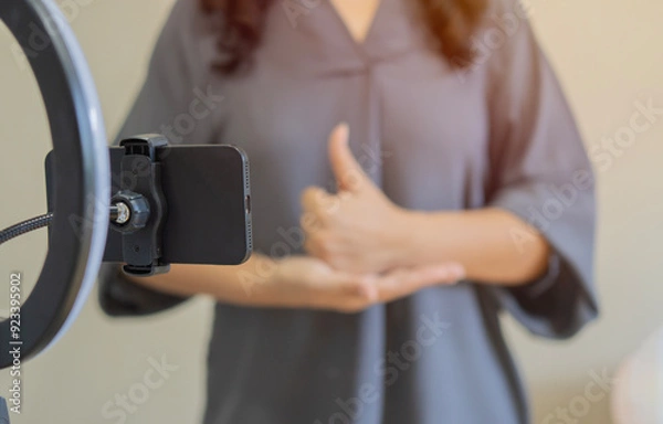 Fototapeta Shot of woman talking and showing sign language while recording video blog for deaf people.