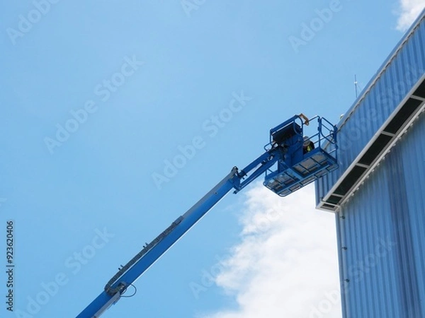 Fototapeta Using a boom truck to work on the roof of a tall building