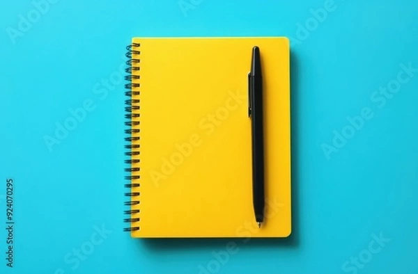 Fototapeta Yellow notebook with pen on blue background