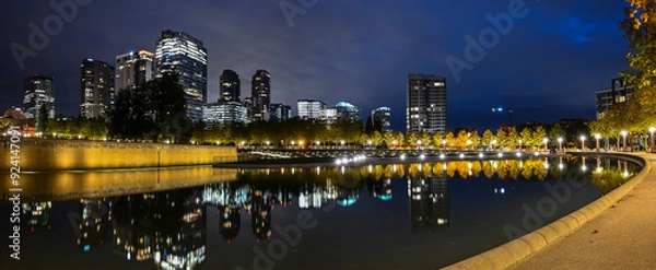 Fototapeta A panoramic early morning, predawn view of the Downtown Bellevue Park with downtown buildings in the background, lights and reflections in the park water feature_10242020_002.