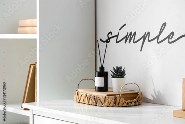 Fototapeta Aroma diffuser, houseplant in wicker tray on table and text SIMPLE on wall in room