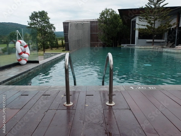 Fototapeta symmetry shape of outdoor swimming pool ladder in front of the blue water in the hotel with the mountain in the background.