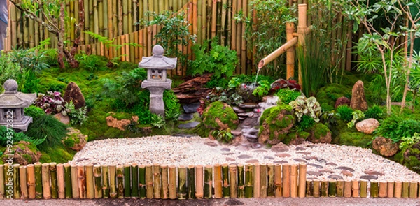 Fototapeta Minimal Japanese garden in home with small stone lantern and bamboo fountain and moss and flowers.
