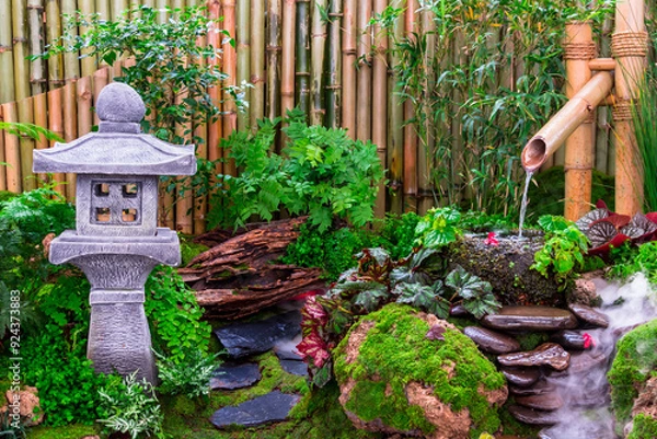 Fototapeta Minimal Japanese garden in home with small stone lantern and bamboo fountain and moss and flowers.
