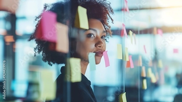 Fototapeta Business colleagues brainstorm using sticky notes and write on glass wall in modern office