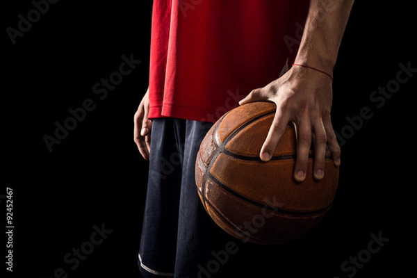 Obraz Player Holds a Basketball ball in one hand isolated on black