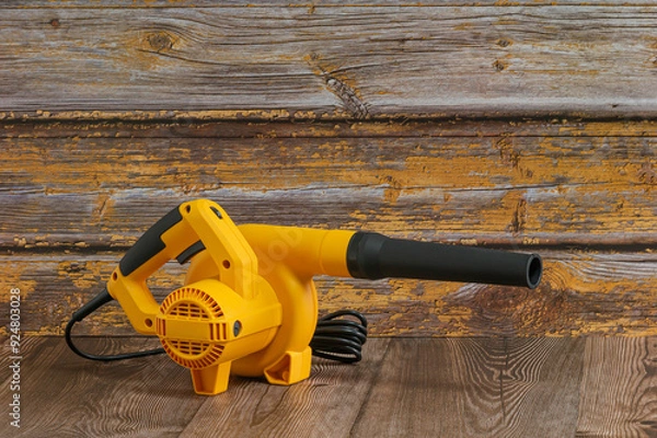 Obraz Yellow electric handheld air blower. It has a long nozzle to be a powerful tool, likely used for cleaning or clearing debris with wooden surfaces.