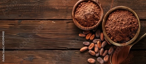 Fototapeta Cocoa powder in a bowl and cocoa beans on a white wooden background top view with copyspace Common ingredients for sweets baked goods and beverages