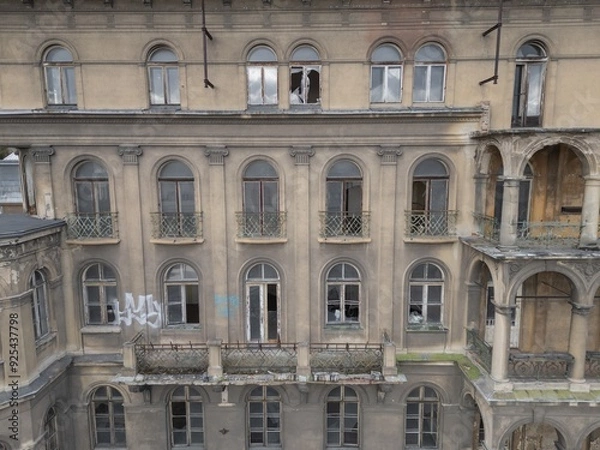 Fototapeta Historic old 19th 20th century ruined derelict abandoned hotel house building  facade scene, with arcade decorated terrace and greek style columns