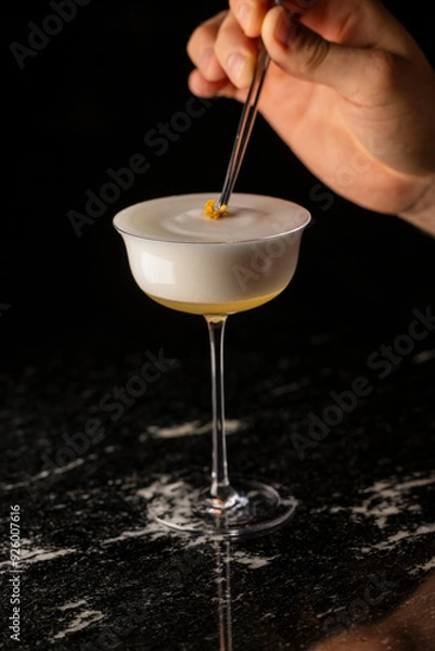Fototapeta coctel en mesa negra en copa coupe y mano poniendo garnish