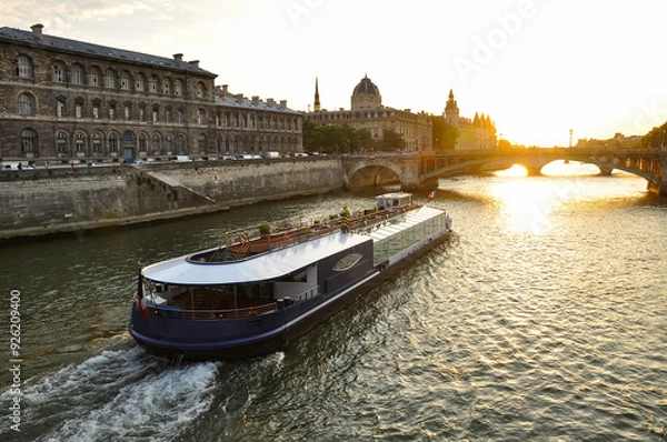 Fototapeta The Seine River in Paris with a historic bridge and the illuminated Eiffel Tower in the background. The calm water reflects the city lights, creating a romantic atmosphere of a Parisian evening