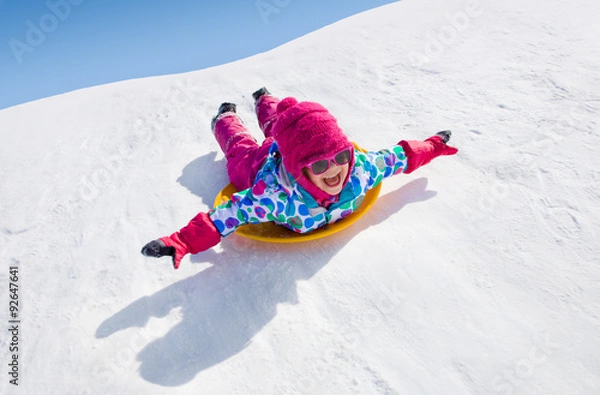 Fototapeta mała dziewczynka jedzie na zjeżdżalniach w okresie zimowym