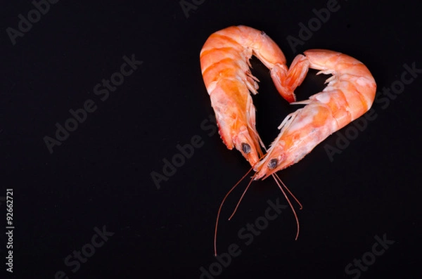 Fototapeta Two shrimps forming a heart isolated in a black background