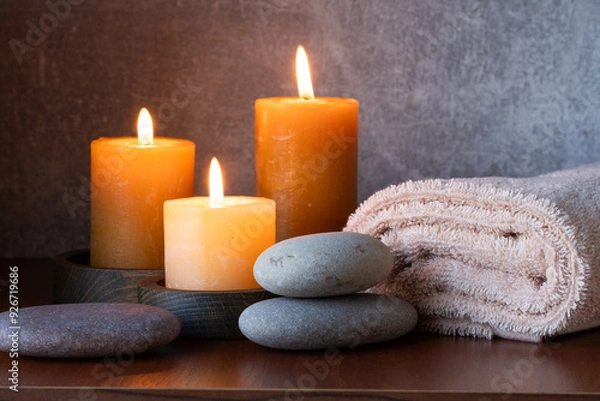 Fototapeta Spa still life with candles, towels and pebbles on wooden background.