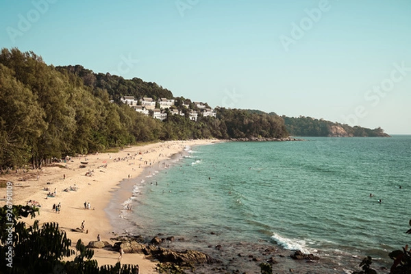 Fototapeta Beautiful view of the Nai Thon Beach in Phuket, Thailand. Tourists are relaxing at the beach and in the crystal clear water. Green trees are standing at the beachfront.