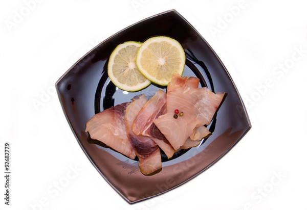 Obraz Smoked swordfish on black plate on a white background seen from above